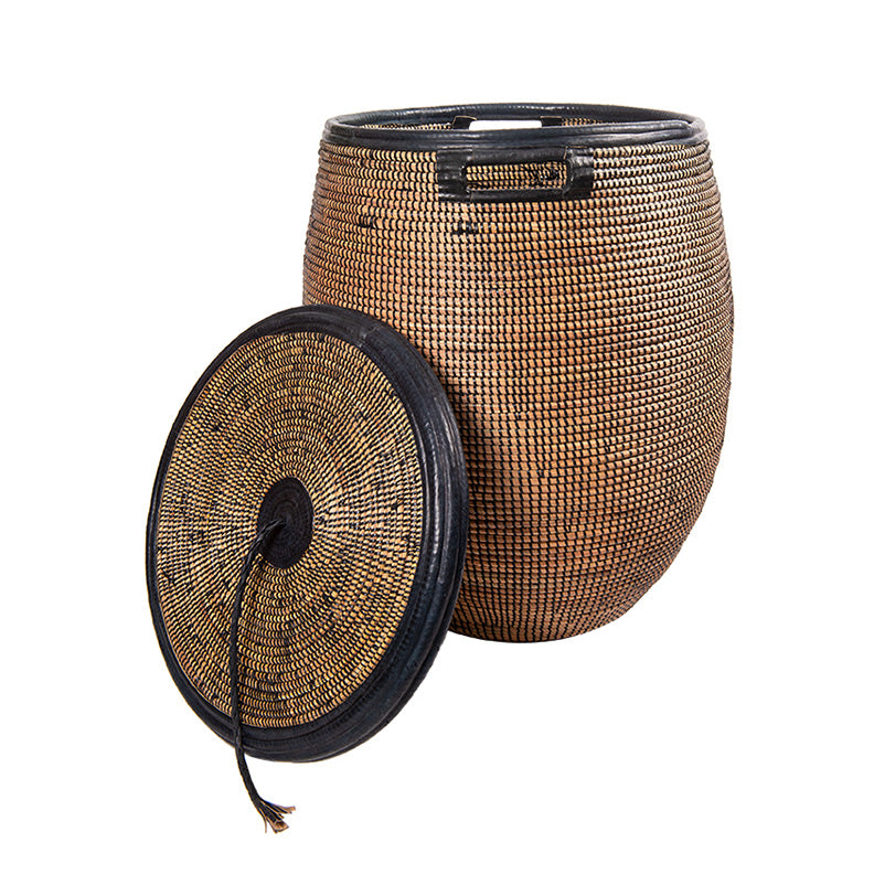 Large rounded woven basket with black detail including black leather trim. Flat lid with a tassel.