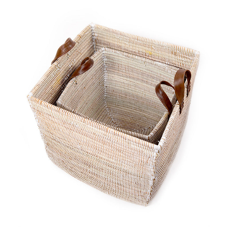 Nested woven baskets with brown leather handles. Baskets are light in color.