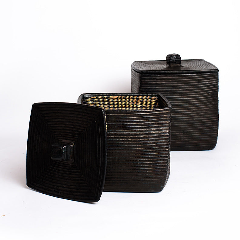 Two square woven baskets with lids and covered in black leather.